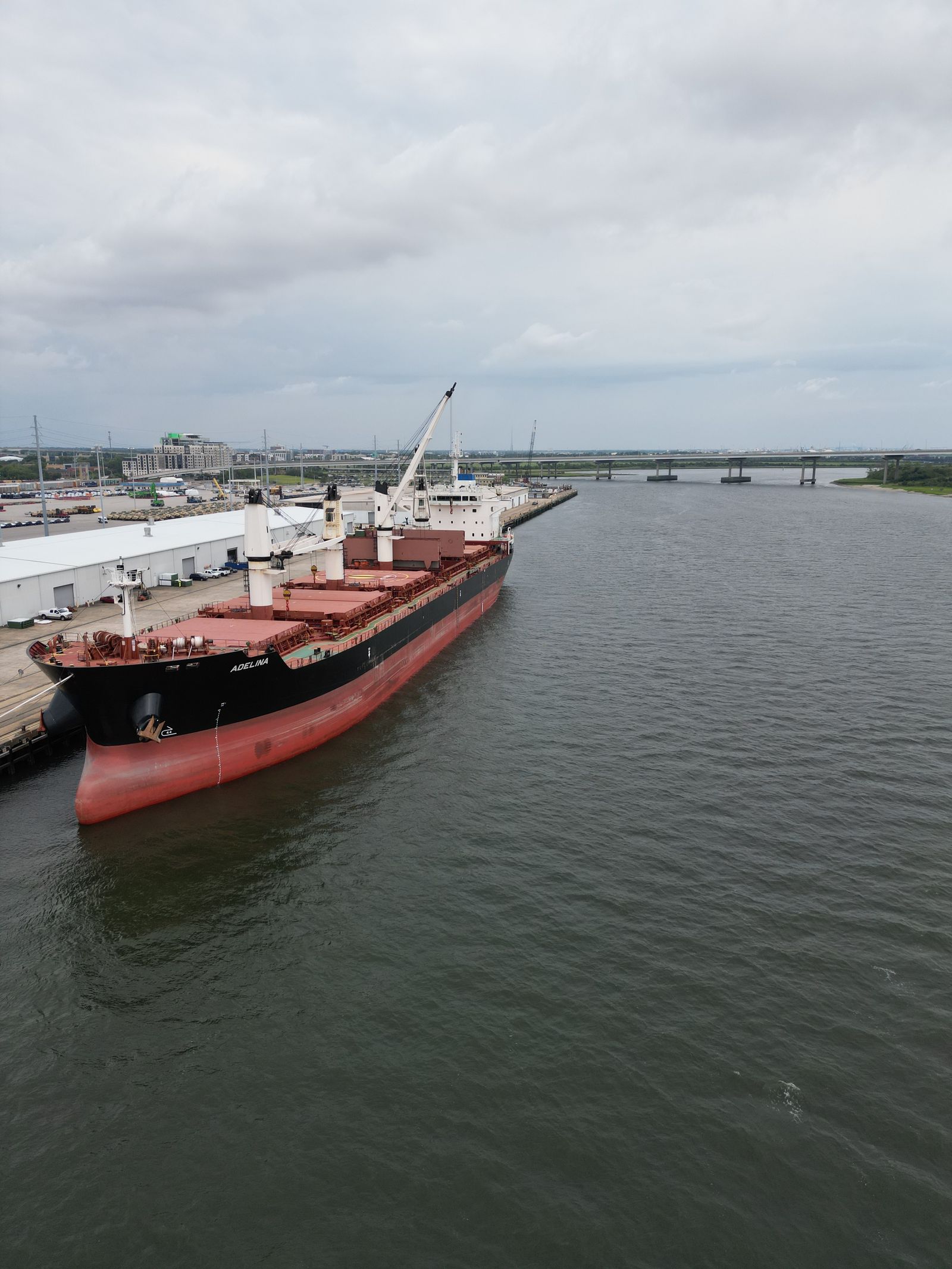 A cargo ship docked at a port terminal, clearly visible in daylight